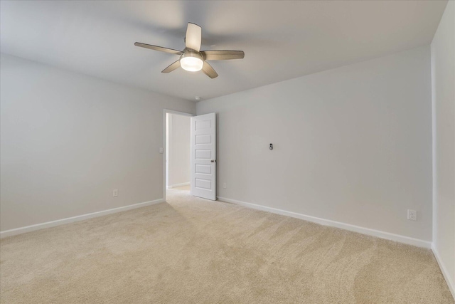 spare room featuring ceiling fan, baseboards, and light colored carpet