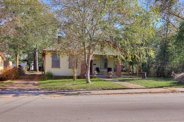 view of property hidden behind natural elements with a porch and a front yard