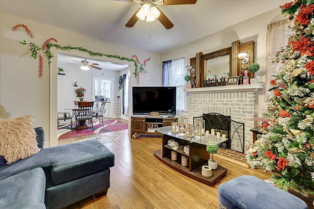 living room with hardwood / wood-style floors, ceiling fan, and a fireplace