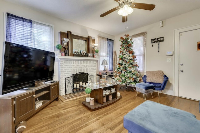 living room featuring a fireplace, light hardwood / wood-style flooring, ceiling fan, and a healthy amount of sunlight