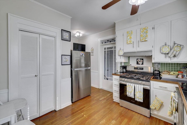 kitchen featuring white cabinetry, light hardwood / wood-style flooring, decorative backsplash, appliances with stainless steel finishes, and ornamental molding