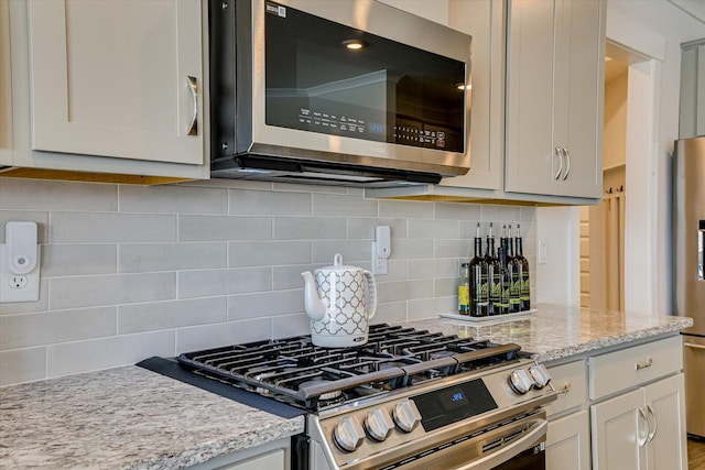 kitchen featuring light stone countertops, stainless steel appliances, and tasteful backsplash