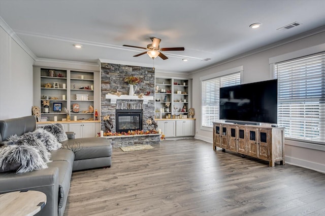 living room featuring a fireplace, built in features, ceiling fan, and a healthy amount of sunlight