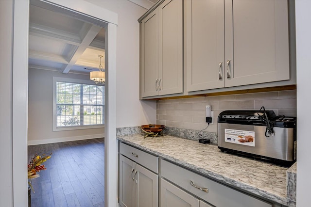 kitchen with beam ceiling, coffered ceiling, light stone counters, wood-type flooring, and decorative backsplash