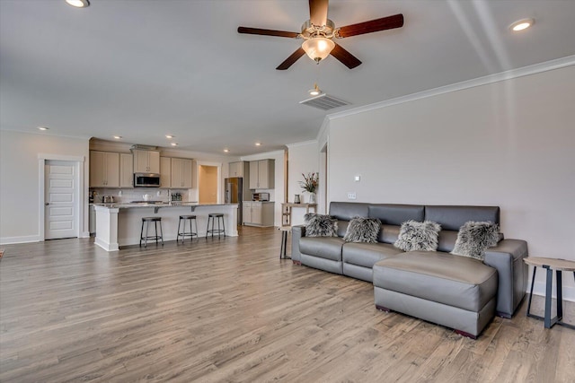 living room with crown molding, light hardwood / wood-style flooring, and ceiling fan