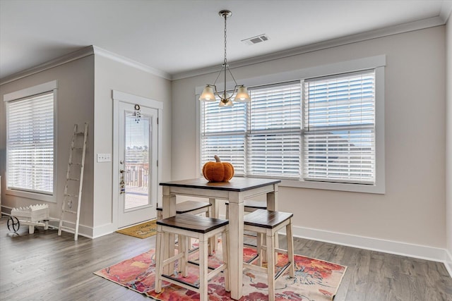 dining space with a chandelier, crown molding, dark wood-type flooring, and a healthy amount of sunlight