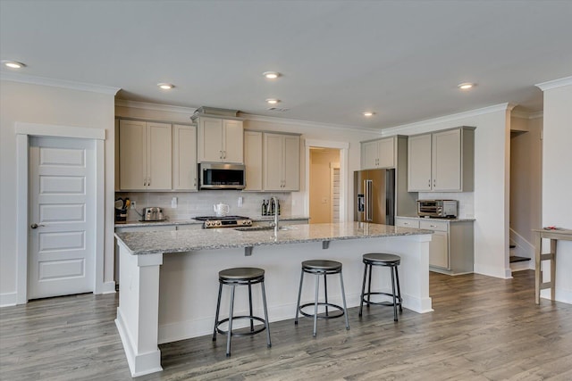 kitchen with sink, stainless steel appliances, a breakfast bar area, and an island with sink