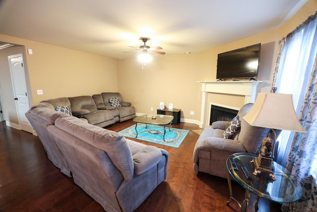 living area with ceiling fan, a fireplace, baseboards, and wood finished floors