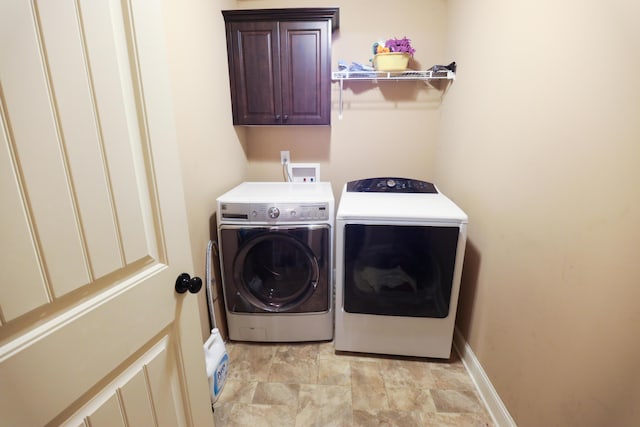 clothes washing area featuring cabinet space, washing machine and dryer, and baseboards