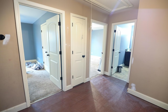 hallway featuring attic access, carpet flooring, wood finished floors, and baseboards