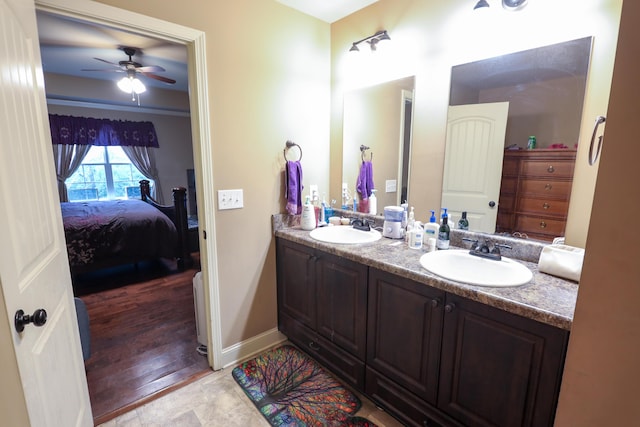 ensuite bathroom featuring double vanity, connected bathroom, a ceiling fan, and a sink