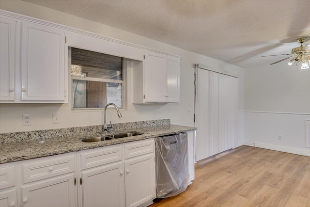 kitchen with sink, dishwasher, white cabinets, and a textured ceiling