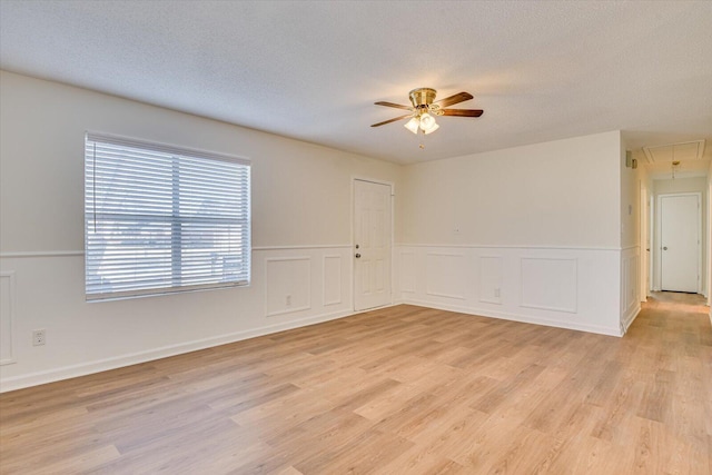 unfurnished room with a textured ceiling, light hardwood / wood-style flooring, and ceiling fan