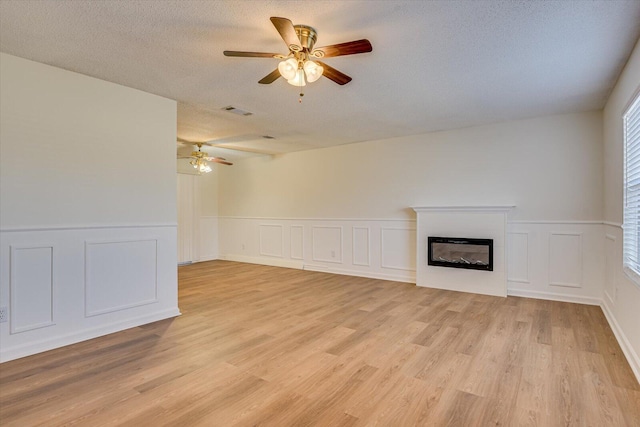 unfurnished living room featuring ceiling fan, a textured ceiling, and light wood-type flooring