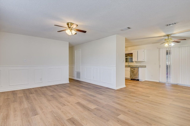 unfurnished living room with ceiling fan, light hardwood / wood-style floors, and a textured ceiling