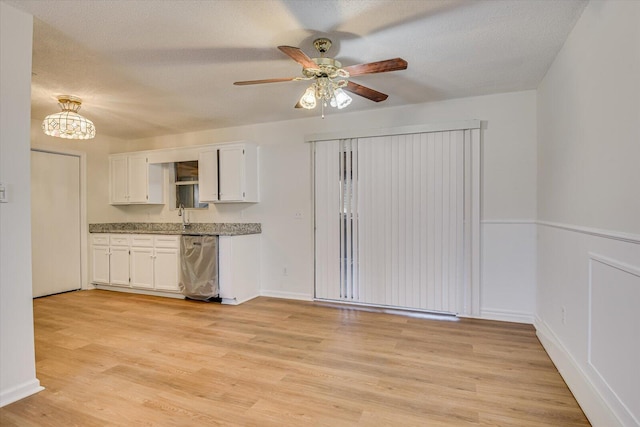 kitchen featuring a textured ceiling, stainless steel dishwasher, white cabinets, light wood-type flooring, and ceiling fan with notable chandelier