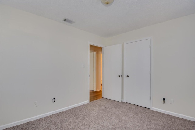 unfurnished bedroom featuring light carpet and a textured ceiling