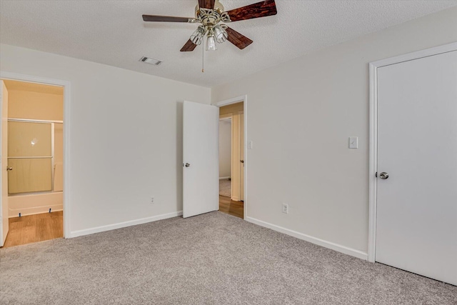 unfurnished bedroom featuring ceiling fan, a textured ceiling, ensuite bath, and carpet flooring