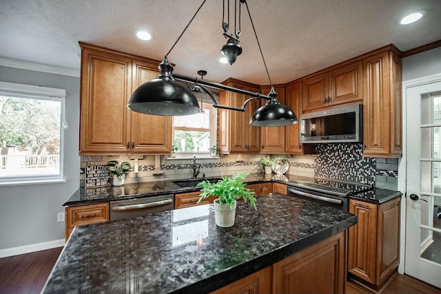 kitchen with stainless steel appliances, hanging light fixtures, dark stone counters, and sink