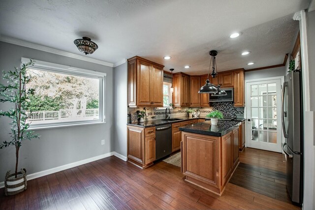 kitchen with sink, a center island, stainless steel appliances, backsplash, and decorative light fixtures