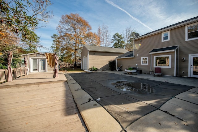 wooden terrace featuring a covered pool, an outdoor structure, a patio, and french doors