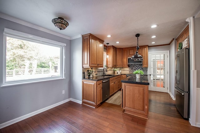 kitchen featuring sink, hanging light fixtures, decorative backsplash, appliances with stainless steel finishes, and a kitchen island