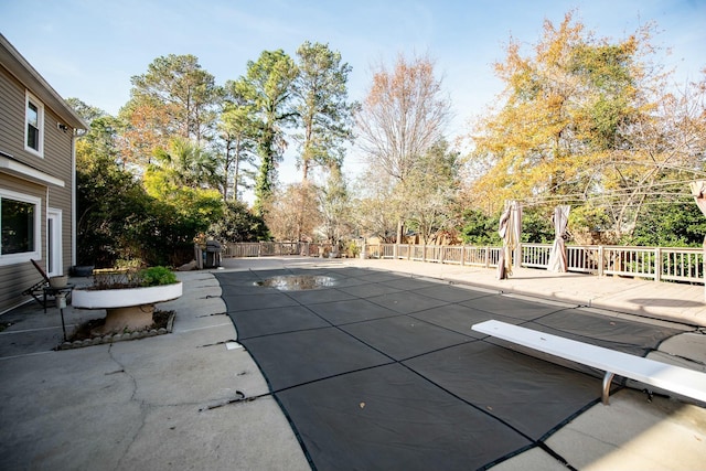 view of pool with a diving board and a patio