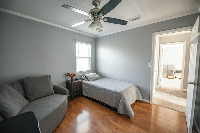 bedroom featuring ceiling fan, crown molding, and hardwood / wood-style flooring