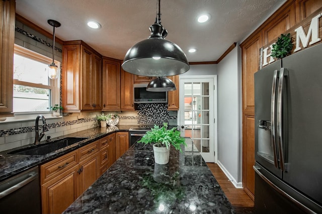 kitchen featuring sink, stainless steel appliances, dark hardwood / wood-style flooring, dark stone counters, and decorative light fixtures