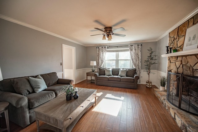 living room with hardwood / wood-style floors, ceiling fan, crown molding, and a fireplace