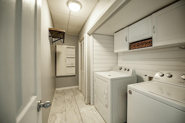 laundry area with wood walls, cabinets, and separate washer and dryer