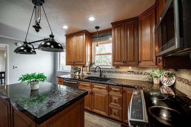 kitchen with decorative light fixtures, a kitchen island, dishwasher, and sink