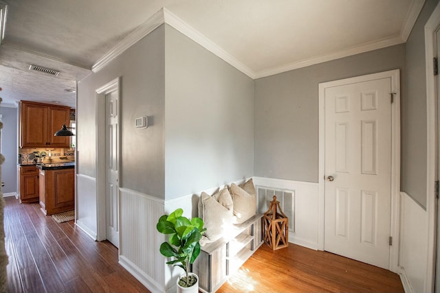 hall with dark wood-type flooring and ornamental molding