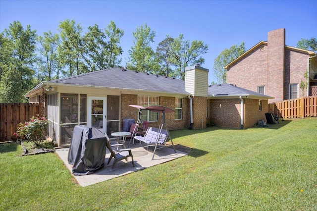 back of house featuring a patio area, a fenced backyard, a sunroom, and a lawn