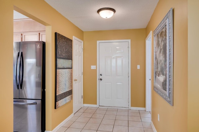 interior space with light tile patterned floors, a textured ceiling, and baseboards