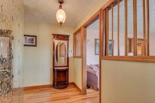 hallway with a textured ceiling and light wood-type flooring