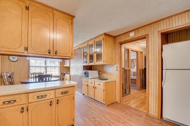 kitchen with a textured ceiling, white appliances, light hardwood / wood-style flooring, and wooden walls