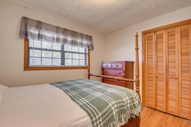 bedroom featuring a closet, light hardwood / wood-style floors, and a textured ceiling