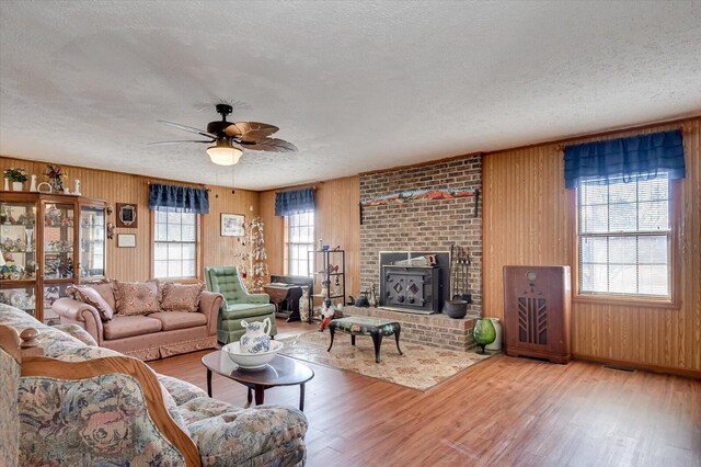 living room with hardwood / wood-style floors, a textured ceiling, ceiling fan, and wood walls