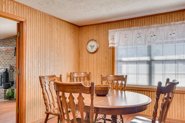 dining area featuring wood walls, wood-type flooring, and a textured ceiling