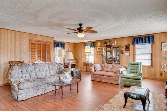 living room featuring hardwood / wood-style flooring, ceiling fan, and a textured ceiling