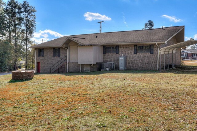 rear view of house with a carport, a yard, and central AC