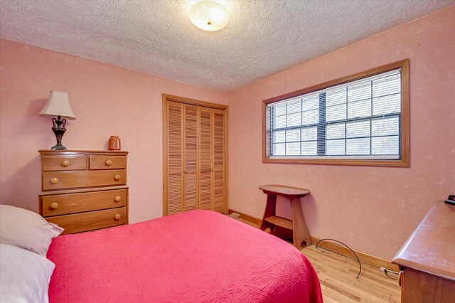 bedroom with a closet, a textured ceiling, and light wood-type flooring