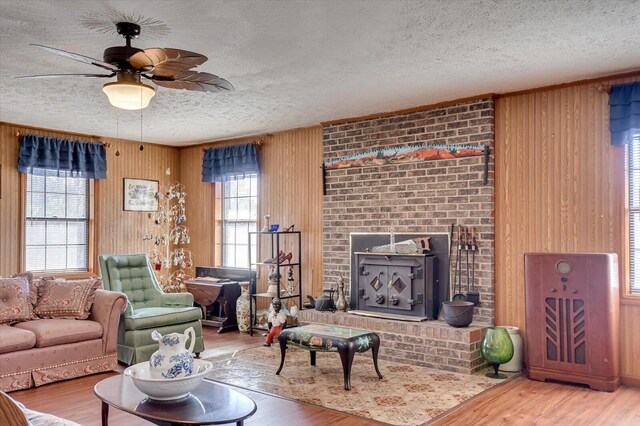 living room with hardwood / wood-style floors, a textured ceiling, a wood stove, and a wealth of natural light