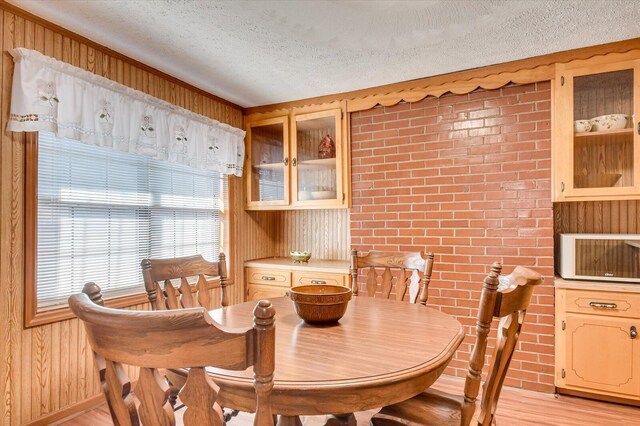 dining area with wooden walls, light hardwood / wood-style flooring, and a textured ceiling