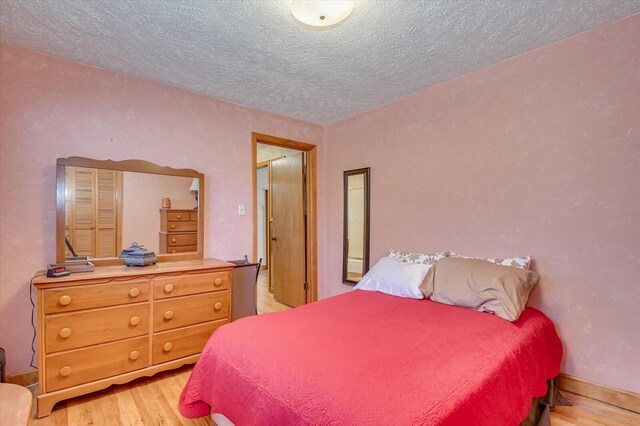 bedroom featuring light hardwood / wood-style floors and a textured ceiling