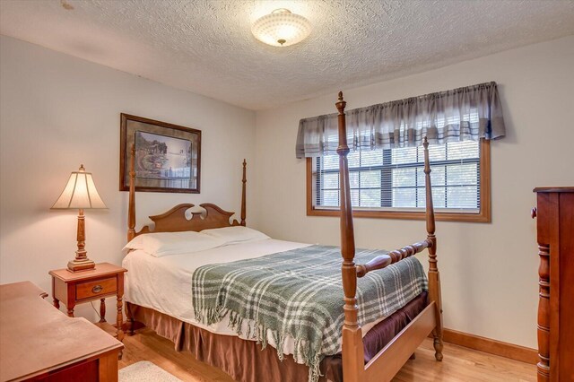 bedroom with a textured ceiling and light hardwood / wood-style floors