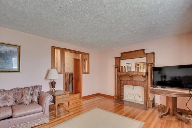 living room featuring hardwood / wood-style floors, a textured ceiling, and a brick fireplace