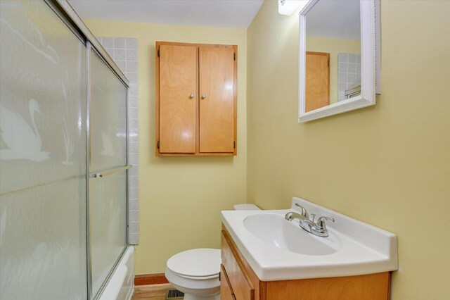 full bathroom featuring vanity, bath / shower combo with glass door, and toilet