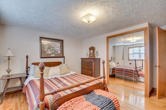 bedroom with light hardwood / wood-style floors, a textured ceiling, and a closet